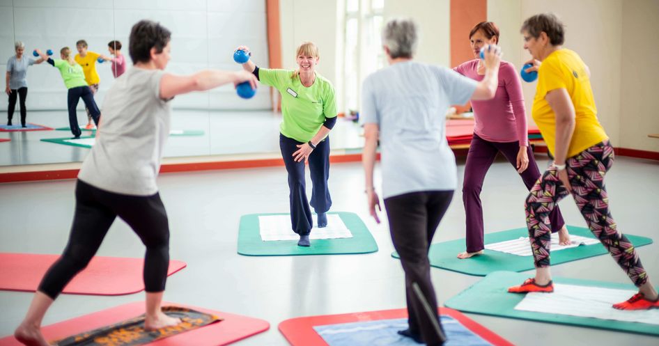 Therapeutin trainiert mit Pateintengruppe in der Bewegungstherapie