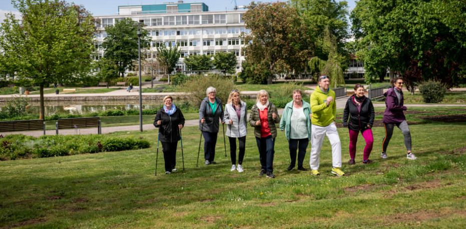 Patientengruppe und Therapeut beim Nordic Walking in der Nähe der Klinik
