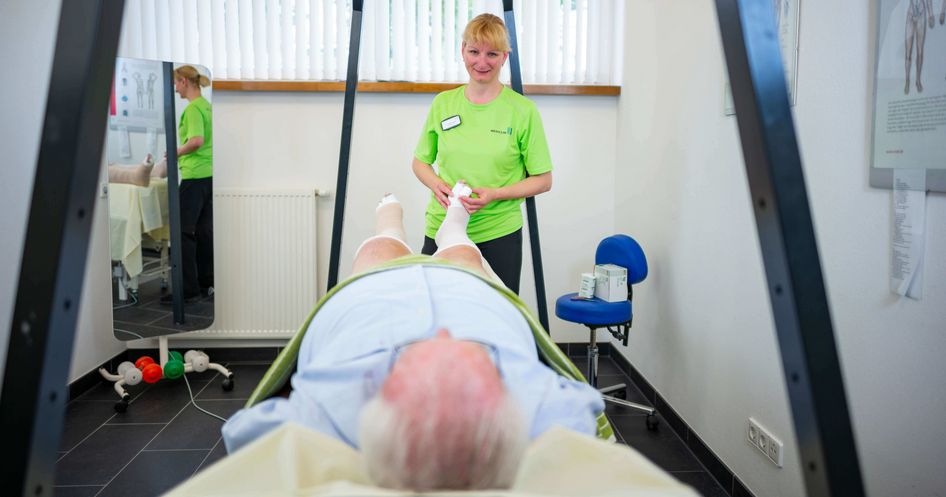 Therapeutin massiert den Fuß eines Patienten