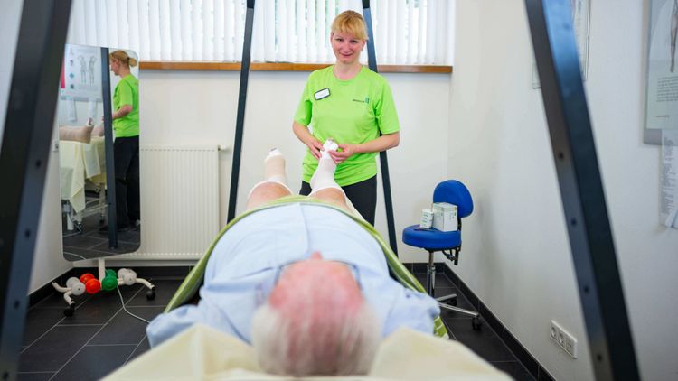 Therapeutin massiert den Fuß eines Patienten